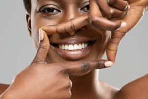 Close-up of a smiling person framing their smile with their hands